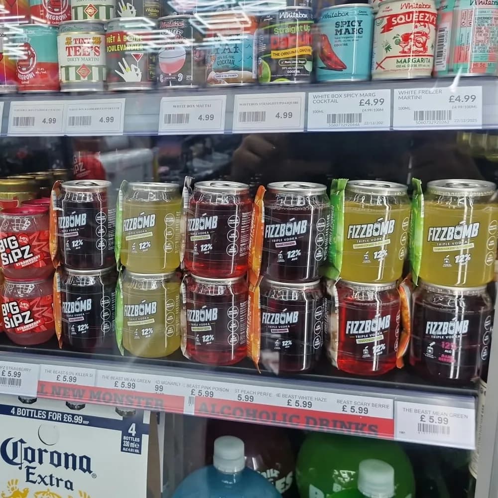 Two rows of FizzBomb cans in all three flavours on a shop fridge shelf, next to Big Sipz and BuzzBallz